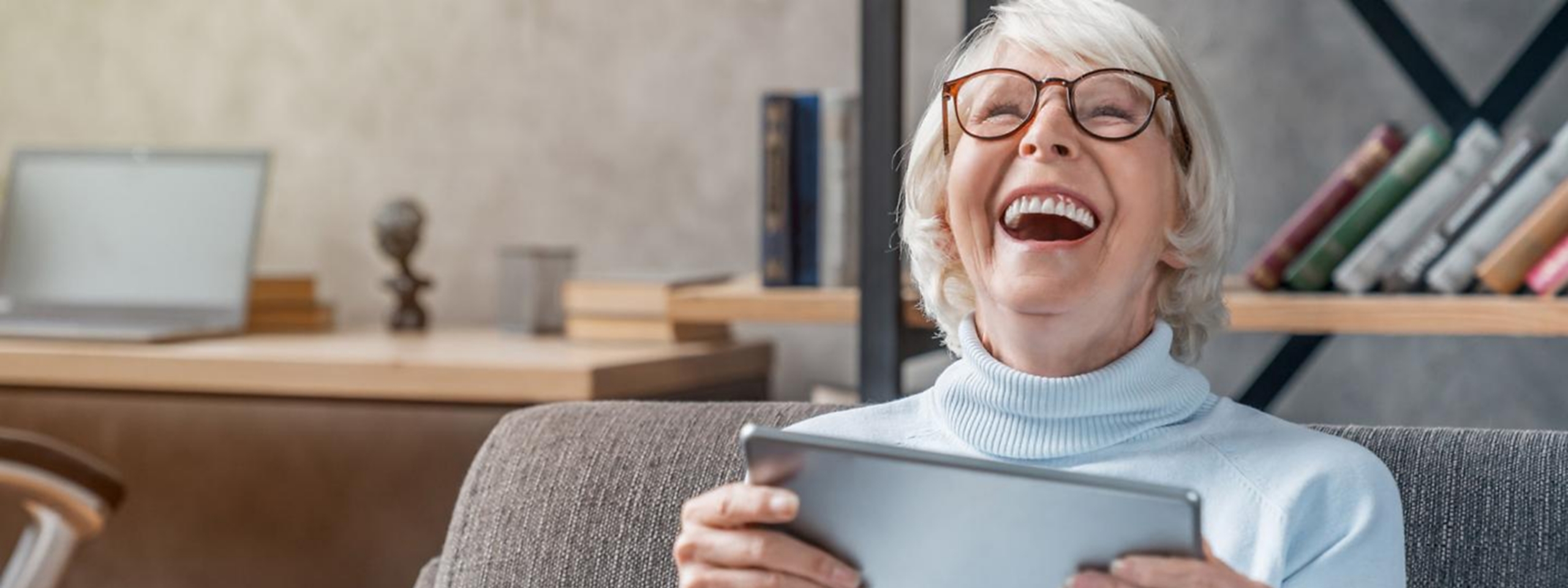 Frau mit Brille und Tablet, lacht. 